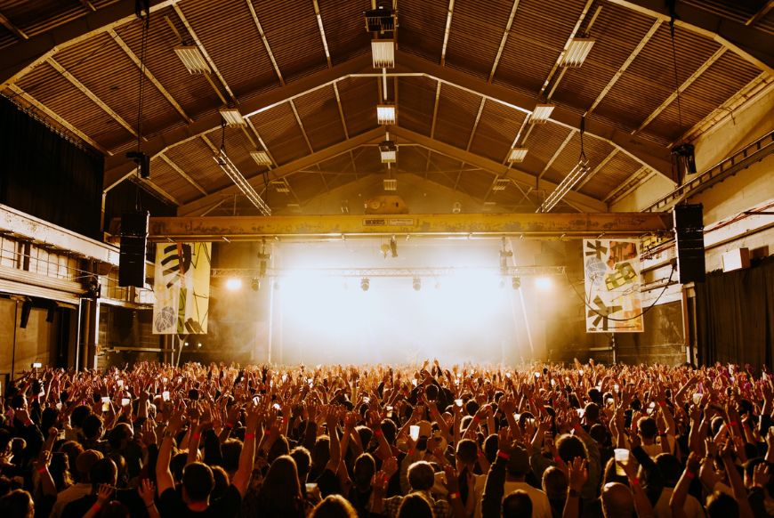 A crowd of people dancing in a warehouse
